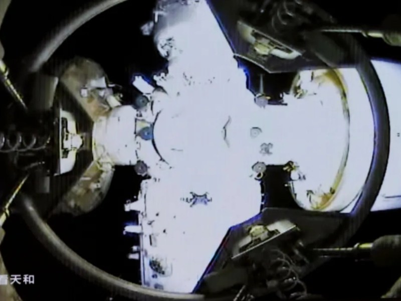 View from Shenzhou-20 spacecraft showing the docking interface with the Tiangong space station on April 24, 2025. The image captures the moment of docking, with structural elements and connection points of both spacecraft visible under bright illumination.