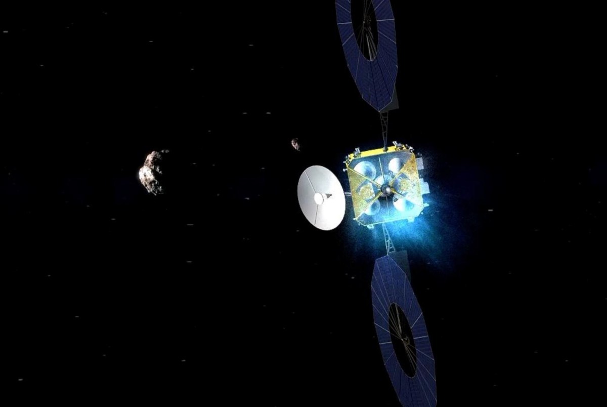 An artistic rendering of China's Tianwen-2 spacecraft approaching an asteroid in deep space. The probe features large circular solar panels, a dish antenna, and an ion propulsion system emitting a blue glow. A small asteroid is visible in the background, set against the vast darkness of space.